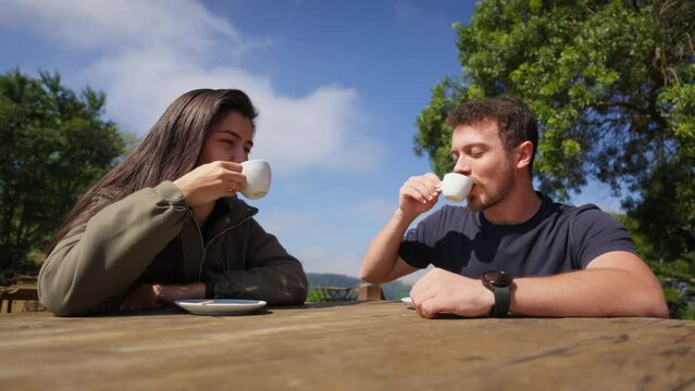 Joyful Young Couple Enjoying Coffee Together in a Scenic Outdoor Setting. Lovers Toasting with Coffee Cups Outdoors.