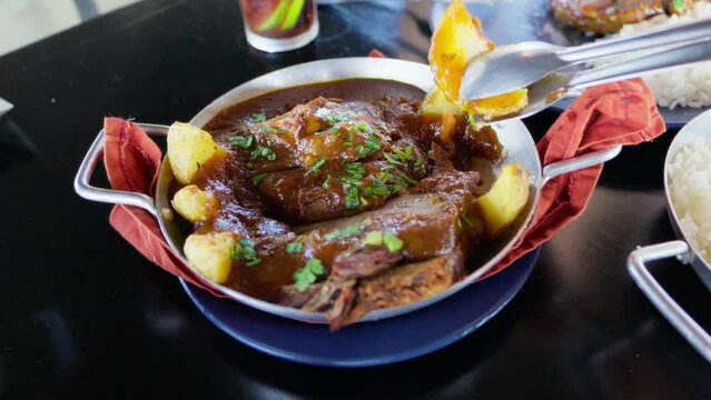 Traditional Brazilian Pot Roast with Gravy and Roasted Potatoes. Close-Up of a Person Serving a Savory Pot Roast with Rich Gravy and Roasted Potatoes