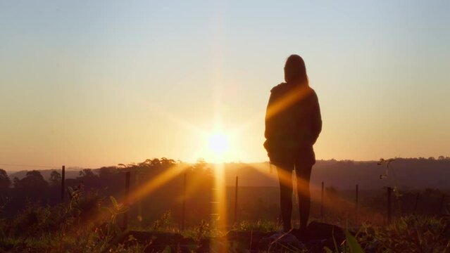 Girl Watching Sunset on the Horizon. Silhouette of a Young Woman Standing and Gazing at the Sunset in a Rural Setting