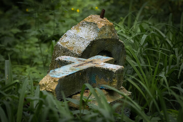 broken, stone cross on the grass