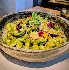 Gniocci with pesto and shrimps on a plate in a restaurant