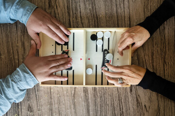 Unrecognizable people playing fast sling puck game on wooden board