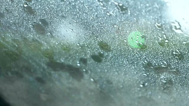 A close-up shot of a car windshield wipers clearing raindrops from the glass.