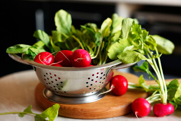 Metal colander with fresh radishes on white table, closeup