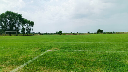 Soccer Football field with very green grass, trees and clouds