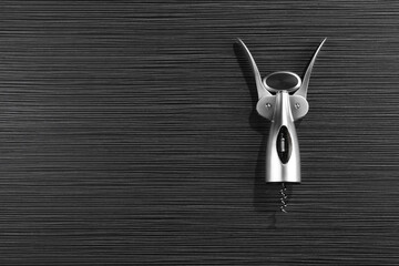 One wing corkscrew on black wooden table, top view. Space for text