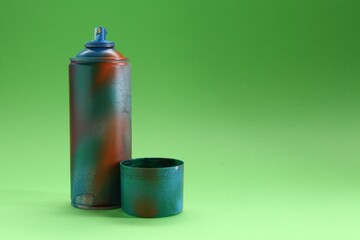 Spray paint can with cap on green background, space for text