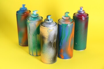 Many spray paint cans on yellow background
