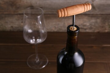 Wine bottle with corkscrew on table, closeup