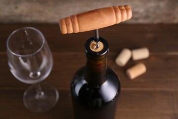 Wine bottle with corkscrew on table, closeup