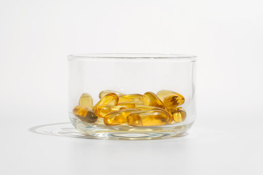Omega 3 capsules in a glass container on white background