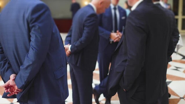 Group of men in business suits talking and discussing during coffee break at conference, politicians and entrepreneurs networking and negotiate, businessmen colleagues have a dialog conversation