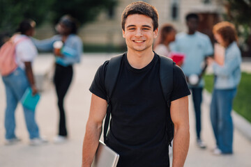Happy college student boy with backpack posing at university campus.