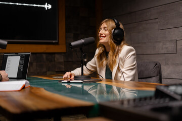 Closeup of young woman in headphones using microphone while working