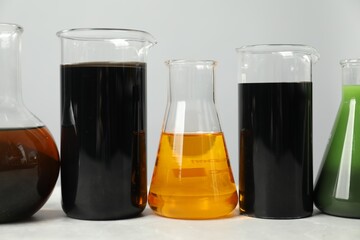 Laboratory glassware with different types of oil on white table, closeup