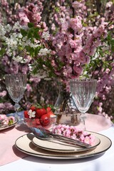 Stylish table setting with beautiful spring flowers in garden