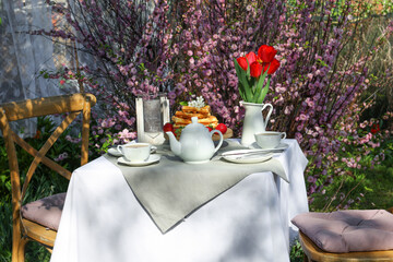 Beautiful bouquet of tulips and freshly baked waffles on table served for tea drinking in garden