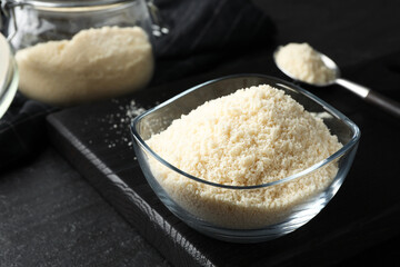 Fresh almond flour in bowl on dark table, closeup