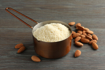 Fresh almond flour in scoop and nuts on wooden table, closeup