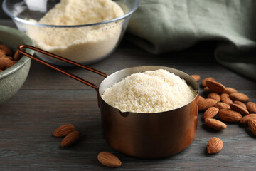 Fresh almond flour in scoop and nuts on wooden table, closeup