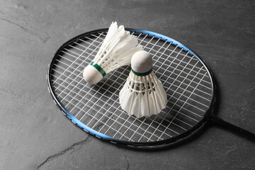 Feather badminton shuttlecocks and racket on grey textured table