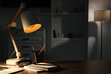 Stylish lamp and stationery on wooden table indoors. Space for text