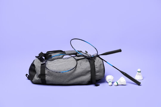 Feather badminton shuttlecocks, rackets and bag on violet background