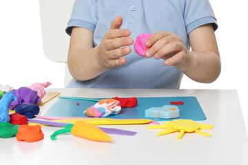 Little boy sculpting with play dough at table on white background, closeup