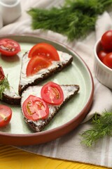 Delicious bruschettas with ricotta cheese, dill and tomatoes on yellow wooden table, closeup