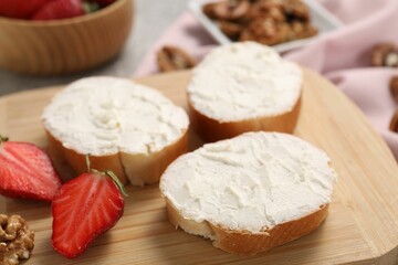 Delicious bruschettas with ricotta cheese, strawberries and walnuts on table, closeup