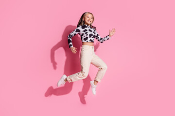 Full length photo of adorable lovely girl wear cowskin outfit jumping high empty space isolated pink color background