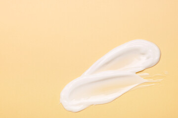 Samples of face cream on pale yellow background, top view. Space for text
