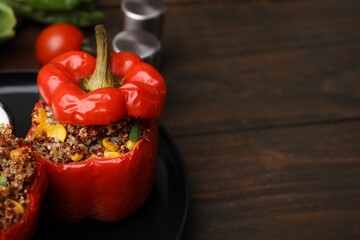 Quinoa stuffed peppers with corn on wooden table, closeup. Space for text
