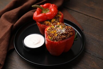 Quinoa stuffed peppers with corn and sauce on wooden table
