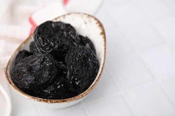 Tasty dried plums (prunes) on white tiled table, closeup. Space for text