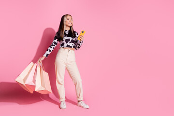 Full length photo of adorable lovely girl wear cowskin outfit rising shoppers typing gadget empty space isolated pink color background