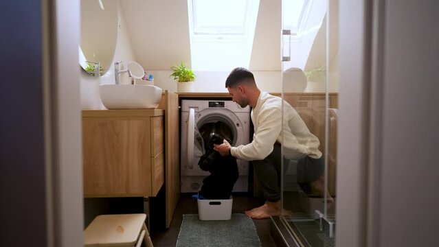Young man using washing machine at laundry room