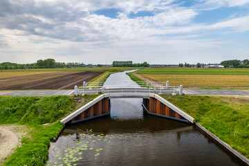 A small bridge over the canal in the middle of fields in The Netherlands.