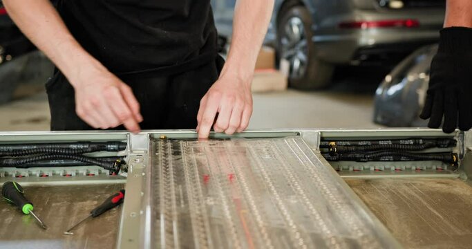 Arabian Male Technician Repairing An EV Car Battery Module In A Workshop. Automobile Engineer Working On An Electric Vehicle Battery Module Separately From The Vehicle. Auto Service