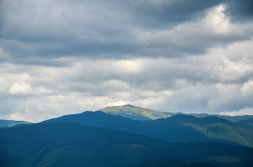 Breathtaking view of the mountain ridge lines and the Pip Ivan (Chornohora) mountain with the ruins of the observatory on top under a low cloudy sky. Carpathian Mountains, Ukraine