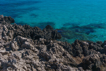 Rocky coast and bay with crystal clear water seen from mediterranean sea on a sunny day, San Vito Lo Capo, Sicily, Italy