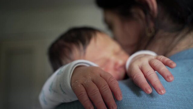 Newborn baby cradled on a woman's shoulder, sleeping soundly. concept of protective and nurturing bond between mother and child, showcasing the tranquility of infancy