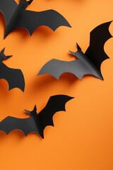 Naklejka premium A group of black paper bats flying against an orange background, creating a vibrant and festive Halloween decoration. Perfect for holiday and seasonal themes.