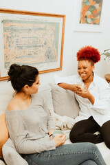 Two woman talk on the couch with coffee