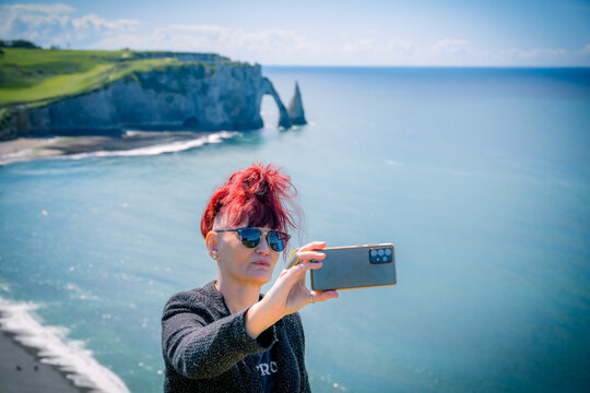 Femme se prenant en photo sur les Falaises d' &Eacute;tretat en Normandie