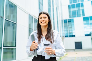 One young successful business woman going to work at business office modern building while holding coffee and laptop	