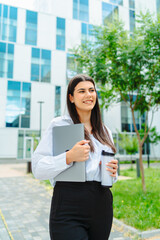 One young successful business woman going to work at business office modern building while holding coffee and laptop	