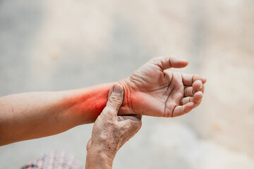 Close-up of an elderly person's hand experiencing wrist pain with a red highlight symbolizing inflammation or arthritis.