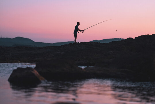 Sunset silohette of a man fishing