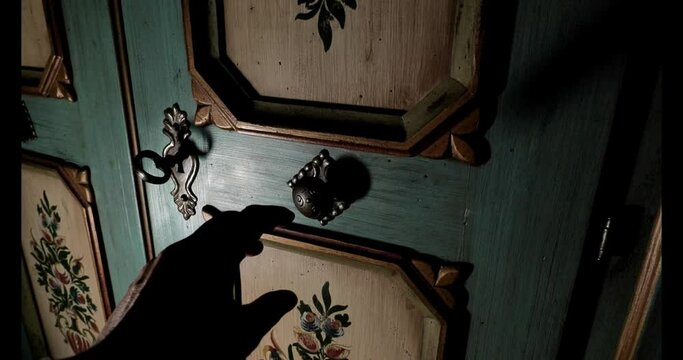 Enigmatic Wooden Door with Key.Opening the Wooden Door with an Old Key.hand opens a wooden antique door with an old key to reveal the secrets of a dark room. 4k footage